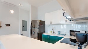 A modern kitchen with white cabinets, a stainless steel refrigerator, a coffee maker, and a microwave. - Casa Love 2B (Panama City)