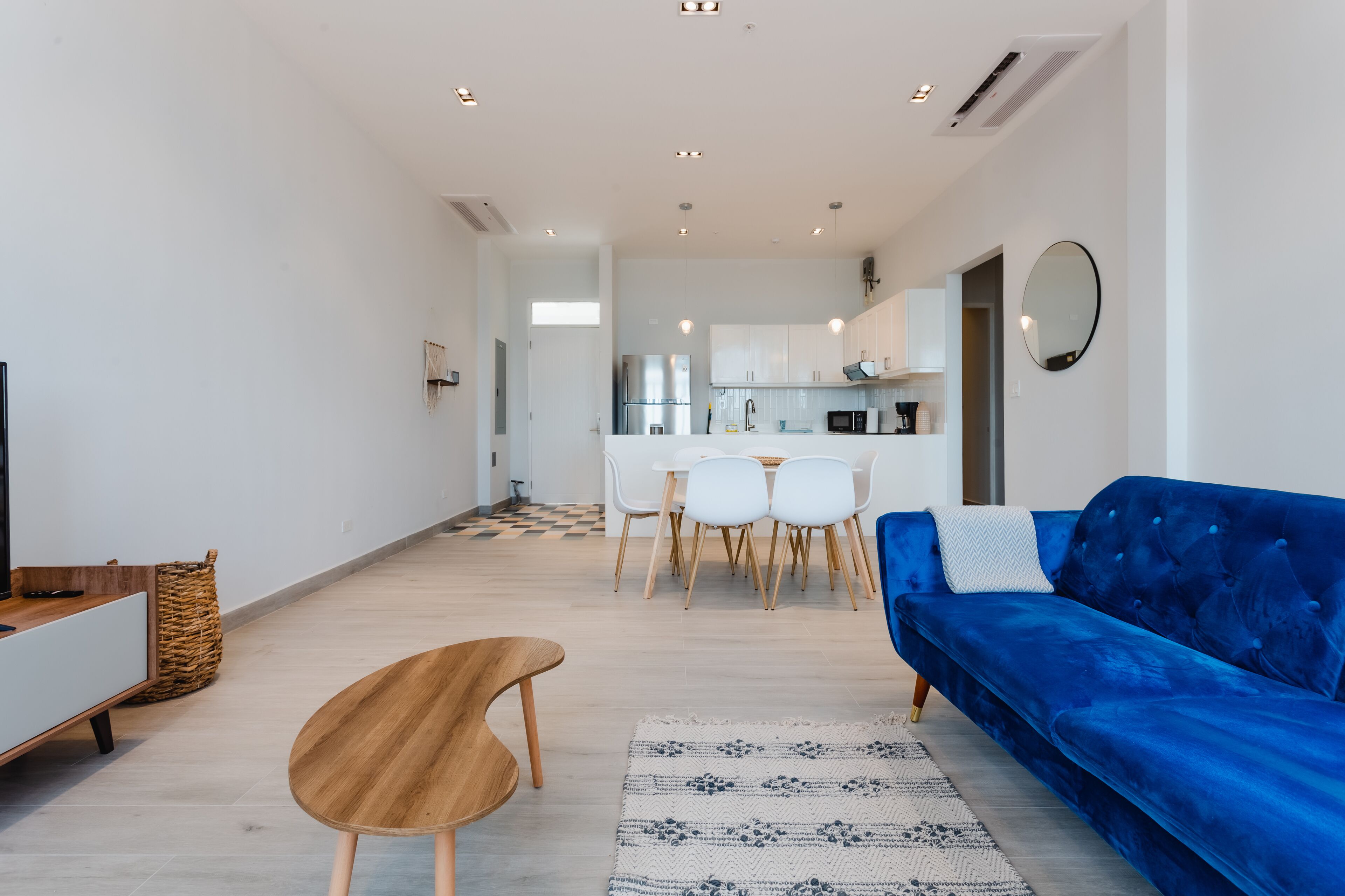 A modern living room with a blue sofa, wooden coffee table, and a patterned rug.