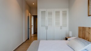A bedroom with a bed, a wooden headboard, a nightstand, and a wardrobe. - Casa Love 2B (Panama City)
