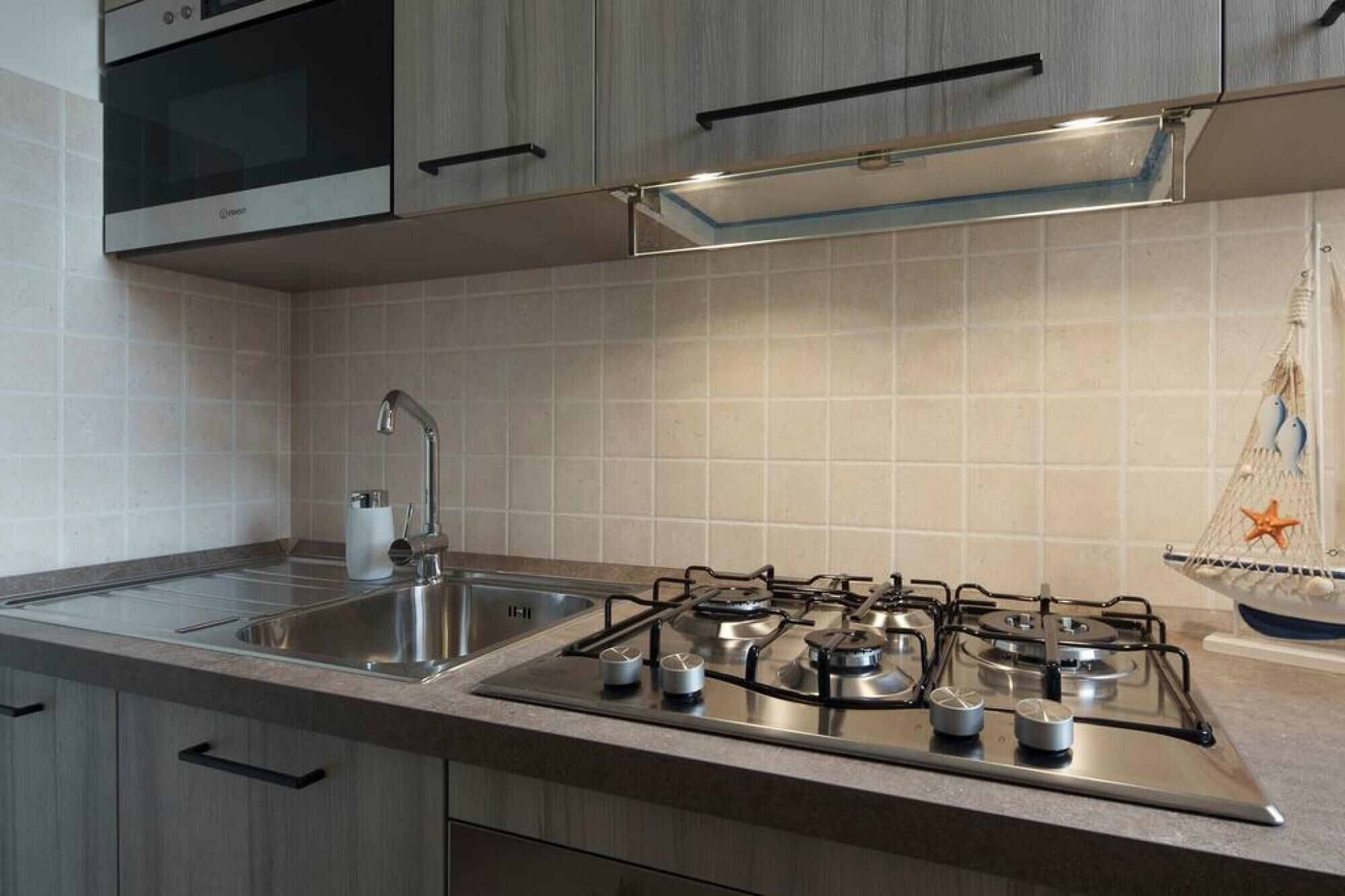 A modern kitchen with a gas stove, stainless steel sink, and wooden cabinets.