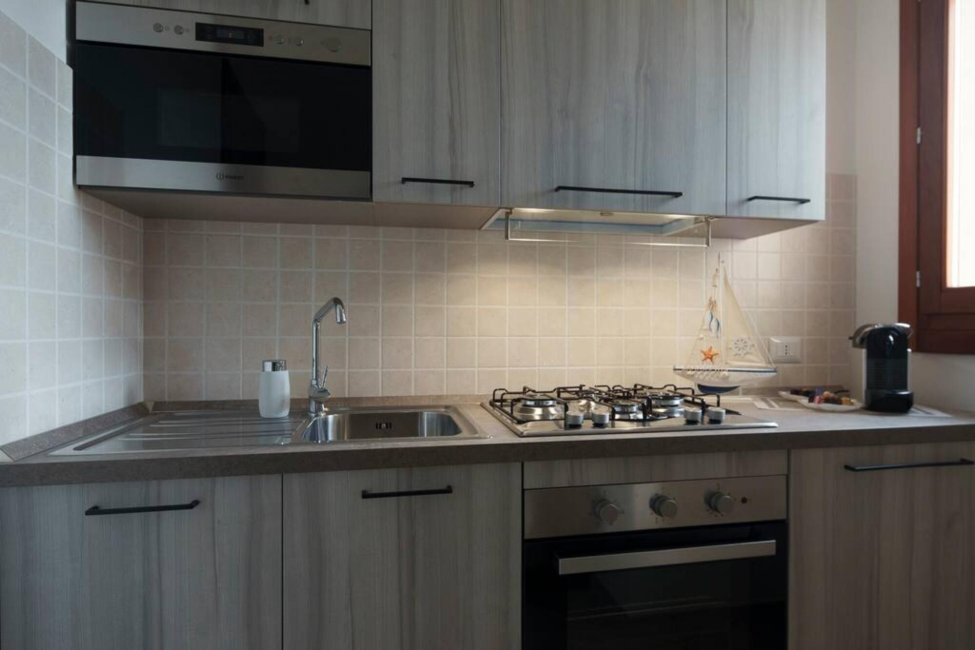 Una cocina moderna con estufa a gas, horno empotrado, electrodomésticos de acero inoxidable y armarios de madera.