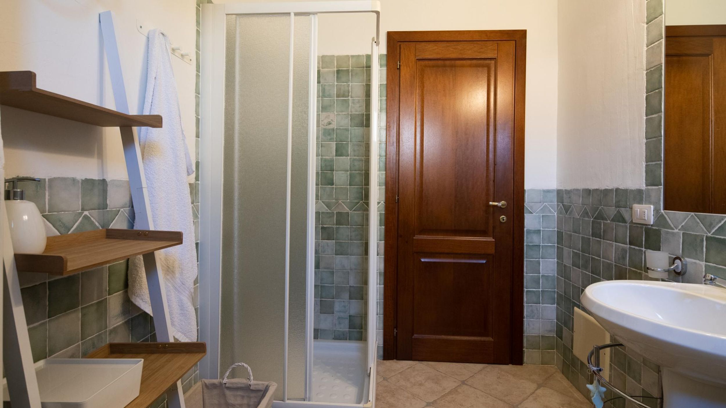 Ein Badezimmer mit Dusche, Waschbecken und einer Holztür.
