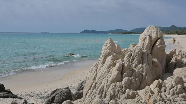 Uma praia com formações rochosas brancas e água turquesa cristalina.