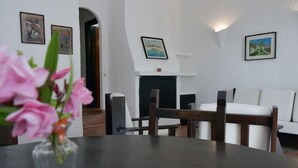 Uma sala de estar moderna com lareira, um sofá e uma mesa de jantar.