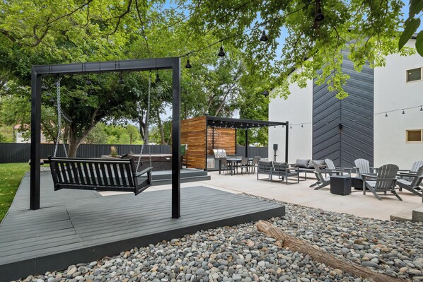 Une terrasse extérieure équipée d’une balançoire, d’un espace salon et d’un barbecue.