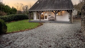 En lille, etetages bygning med skråtag, en overdækket veranda og en grusbelagt indkørsel.