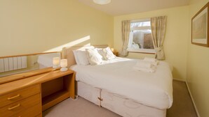 Un dormitorio ordenado con cama, mesita de noche y espejo.