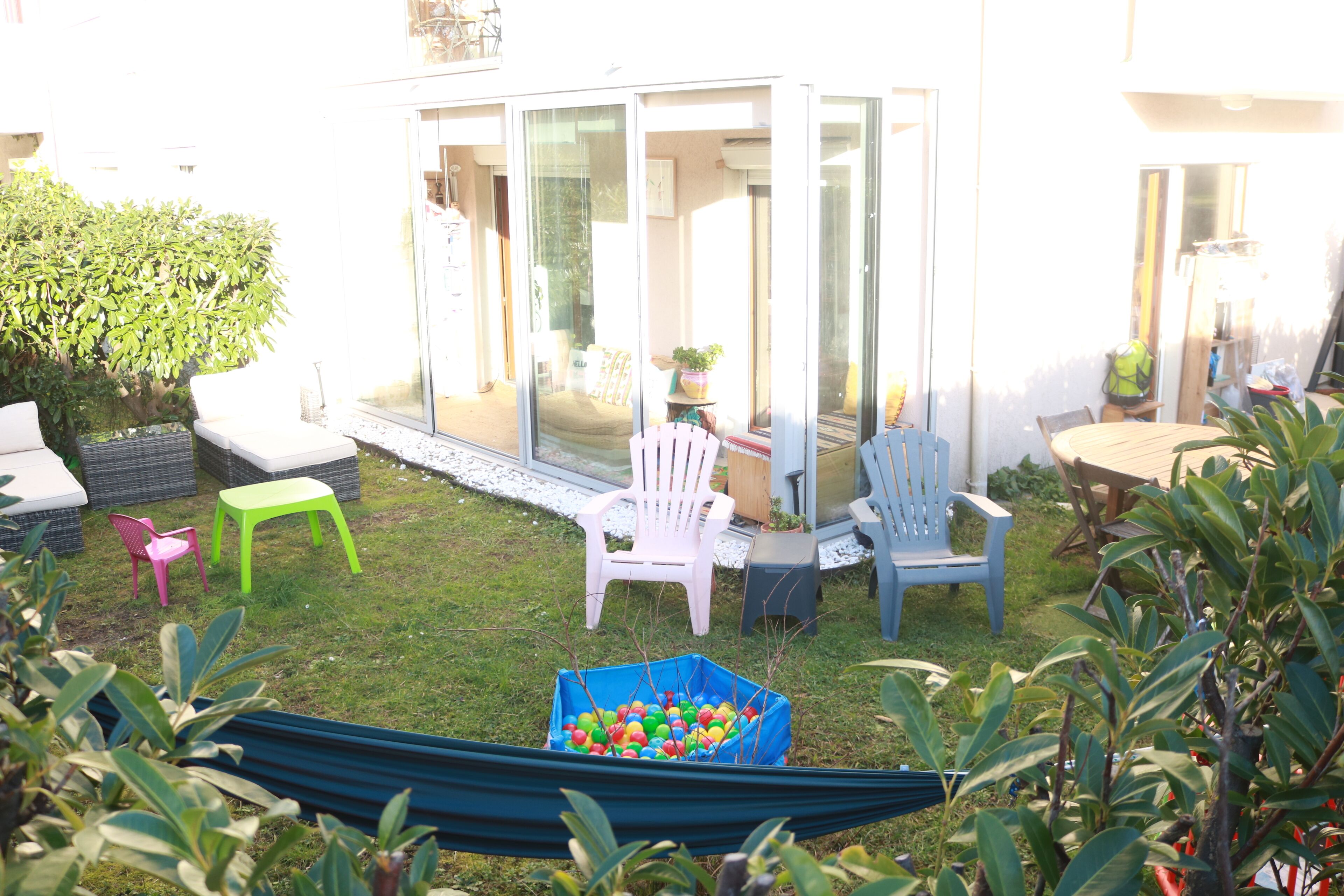 A patio area with outdoor furniture, including chairs and a table, and a play area with colorful balls.