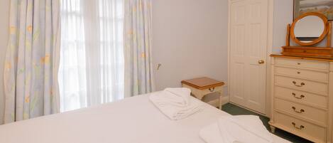 Une chambre à coucher avec un lit, une commode, une petite table et une porte.