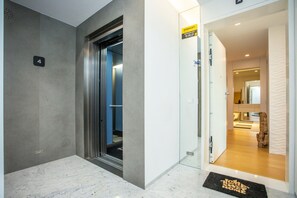 A modern elevator with a digital display, a door labeled "STANLEY," and a doormat with "WELCOME HOME" text. - Acqua House by Rent4all (Figueira da Foz)
