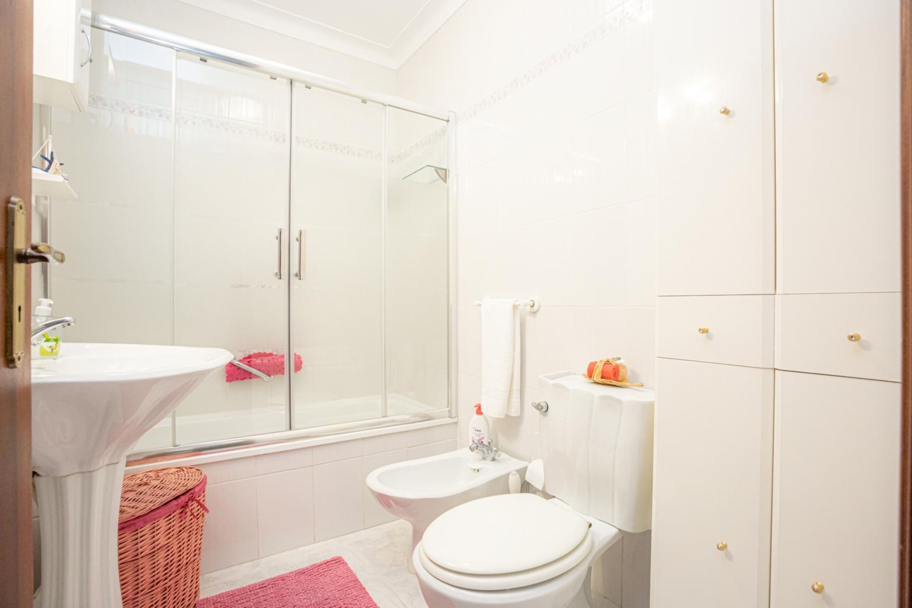 Een badkamer met een douche met glazen wand, een wastafel, een toilet en een bidet.