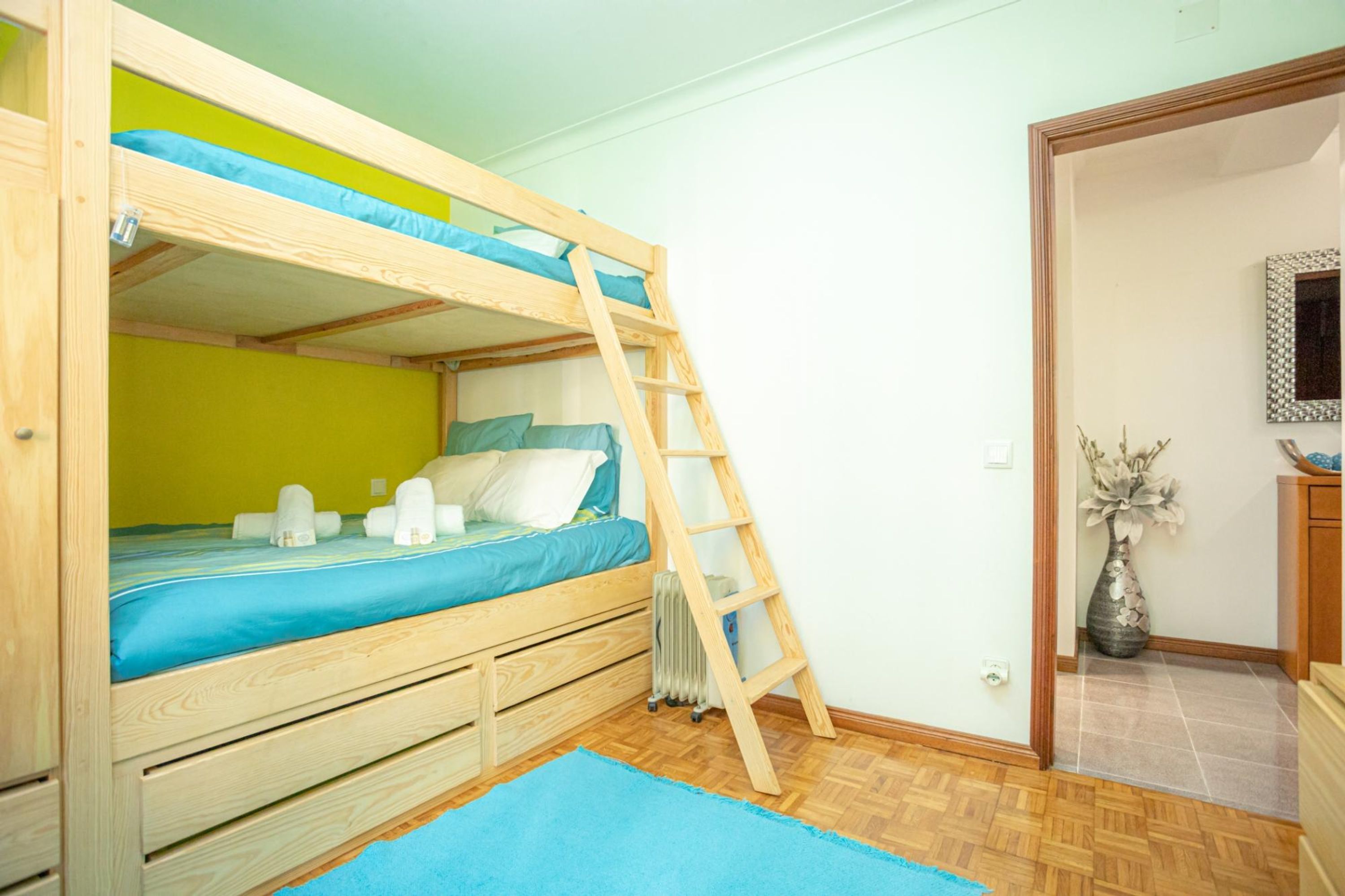 A bunk bed with a ladder, a radiator, and a blue rug.