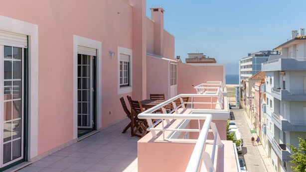 Een roze gebouw met een balkon, een tafel en stoelen.