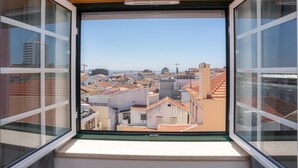Uitzicht vanuit een raam op een dichtbebouwd stadsgebied met verschillende gebouwen en daken.