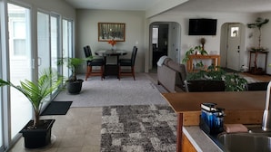 A modern living room with a dining area, a kitchen with a sink, and a TV mounted on the wall. - Fishing / Hunting / Boating - Dream Location -Boats Also Available For Rent  (Grosse Ile Township)