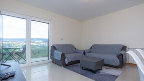 Una sala de estar moderna con dos sofás grises, una mesa de centro y un ventanal que da a un balcón.