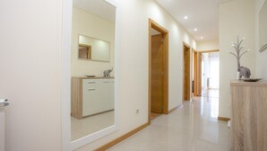 Un pasillo moderno con un espejo grande, puertas de madera y una encimera de mármol.