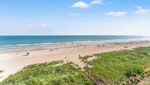A beach with a lifeguard tower, sandy beach, and grassy dunes. - Crescent Towers II 608 - Oceanfront 2 BR Condo (North Myrtle Beach)