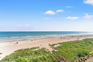 Una playa con una torre de salvavidas, arena y dunas cubiertas de hierba.