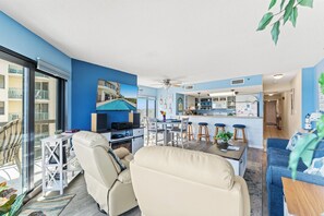 Una sala de estar moderna con un sofá, una mesa de comedor y una zona de cocina con barra.