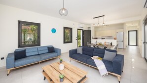 A modern living room with two sofas, a wooden coffee table, and a kitchen in the background. - Villa Petra - Two Bedroom Villa, Sleeps 4 (Afrato)