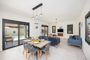 A modern living space with a dining area, sofa, and TV.