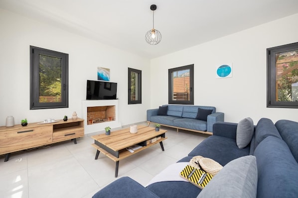 Una sala de estar moderna con chimenea, un sofá, una mesa de centro y un televisor montado en la pared.