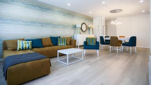 Una sala de estar moderna con un juego de sofá, una mesa de comedor con sillas y un espejo decorativo.