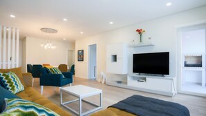 Una sala moderna con un sofá, sillas, una mesa de centro, un televisor y un armario blanco.