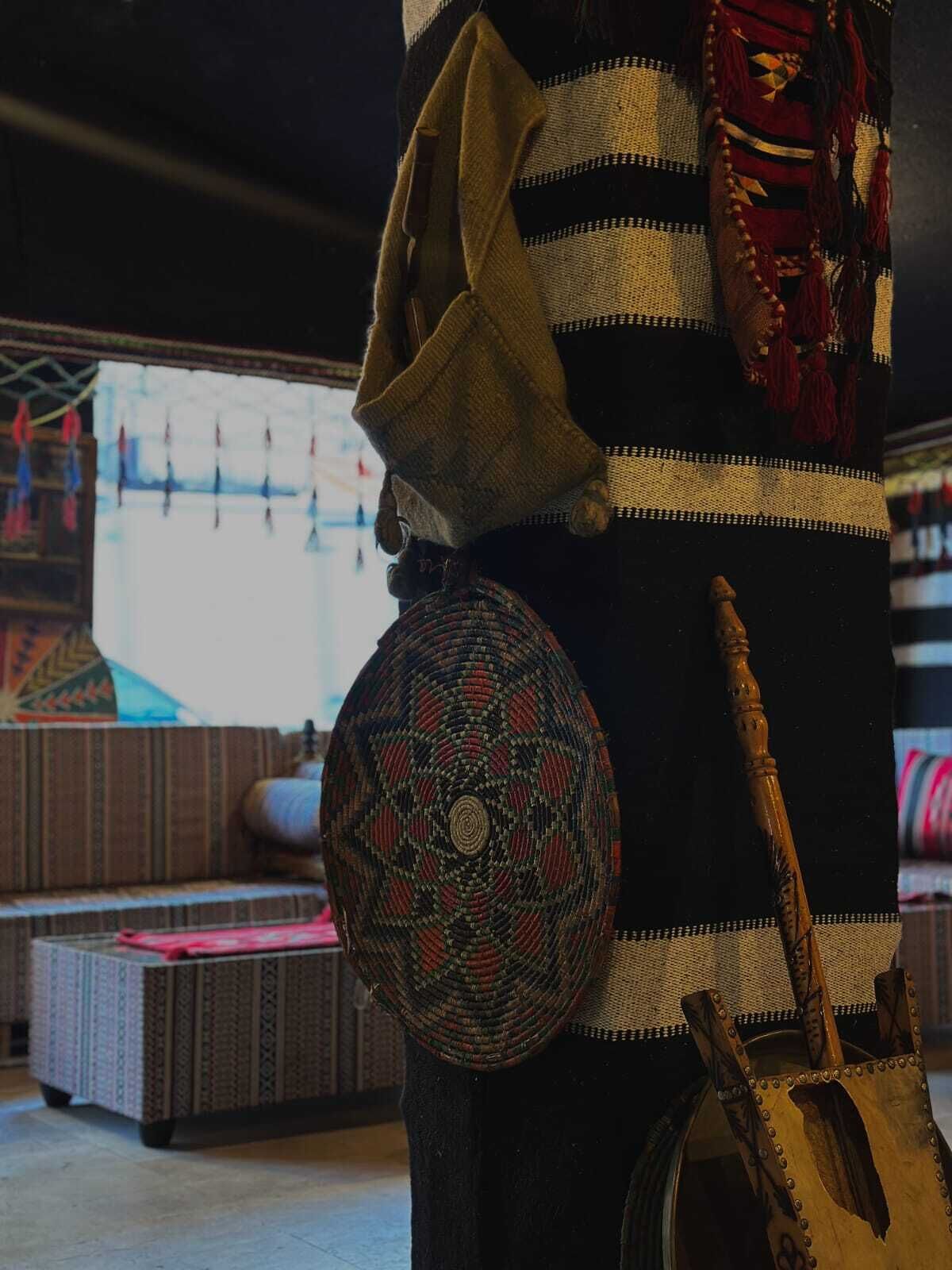 A room with a patterned sofa, a woven basket, and a wooden staff.