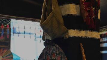 A room with a patterned sofa, a woven basket, and a wooden staff.