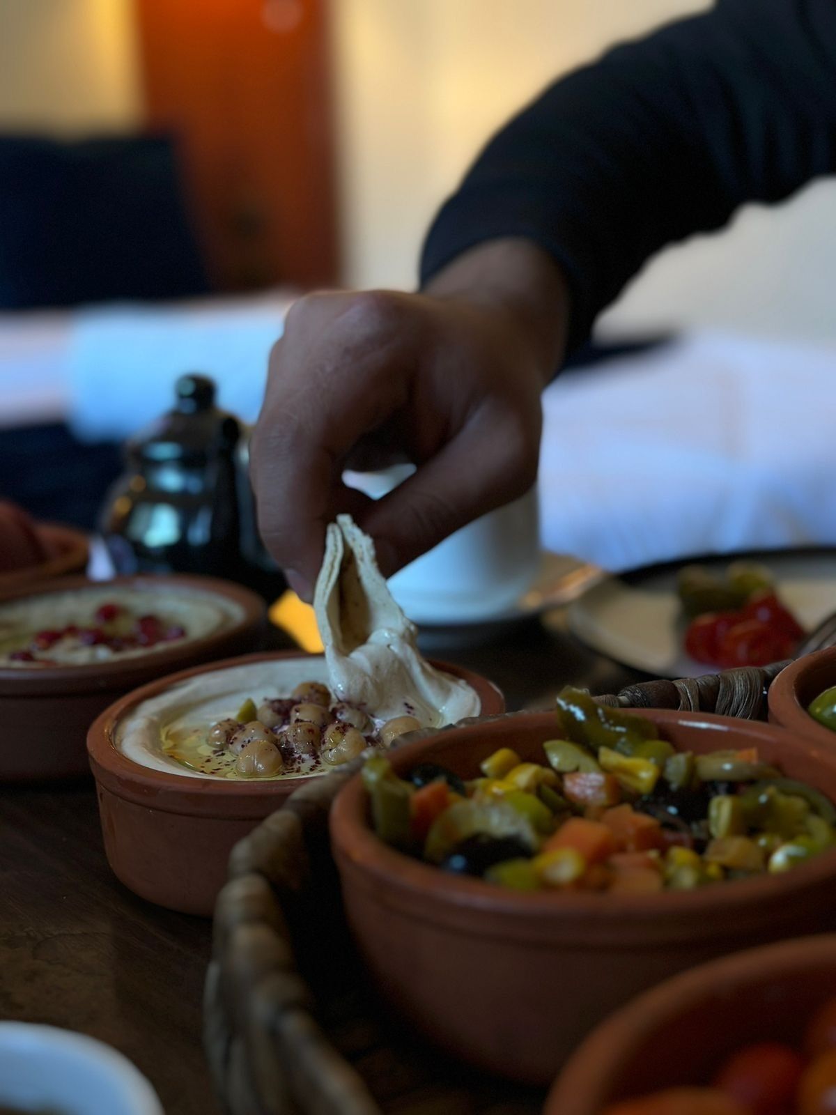 A hand dipping a piece of food into a bowl of soup.