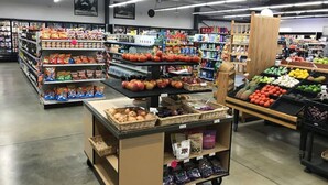 A grocery store with various aisles stocked with snacks, fruits, and vegetables.