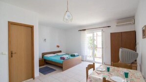 Um quarto pequeno e iluminado, com uma cama, uma mesa e cadeiras, e uma janela.
