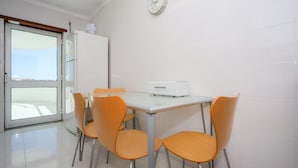 Una habitación con una mesa y sillas, un reloj en la pared y una puerta que da al exterior.