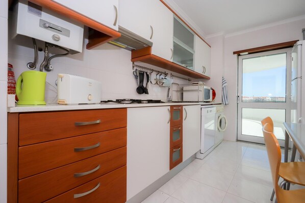 A modern kitchen with white cabinets, a built-in oven, and a window overlooking a cityscape.