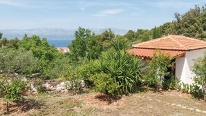 A house with a red-tiled roof, surrounded by greenery and a view of the sea. - Holiday Home Blossom - Four Bedroom Holiday Home With Outdoor Pool and Jacuzzi - (Supetar)