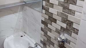 A bathroom with a marble vanity, a sink, and a tiled wall with a mix of white and brown tiles.