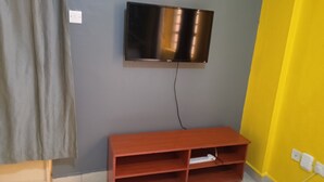 A room with a grey wall, a wooden TV stand, and a mounted TV.