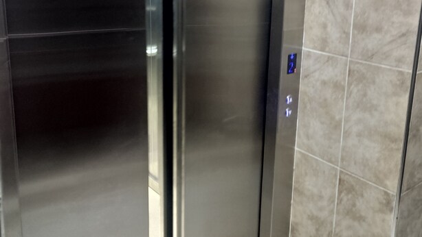 An elevator with metallic doors and a control panel with a digital display.