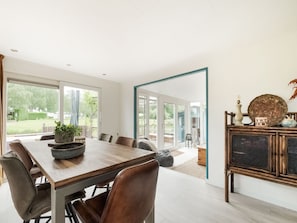 A dining area with a wooden table, leather chairs, and a buffet cabinet with decorative items. - Idyllic Waterfront Vacation Home (Ooltgensplaat)