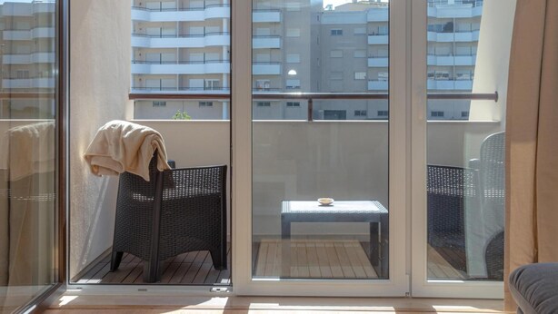 Un balcón con una silla de mimbre, una mesita y una toalla.