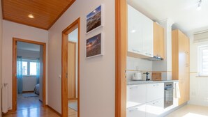 Una cocina moderna con armarios blancos, horno empotrado y una encimera con cafetera.