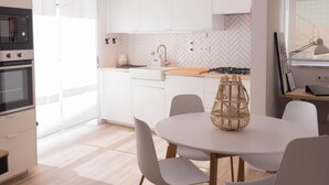 A modern kitchen with white cabinets, a herringbone backsplash, and a round dining table with chairs.