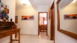 A hallway with wooden furniture, a dining area, and artwork on the walls. - Brasil Avenue by Rent4all (Figueira da Foz)