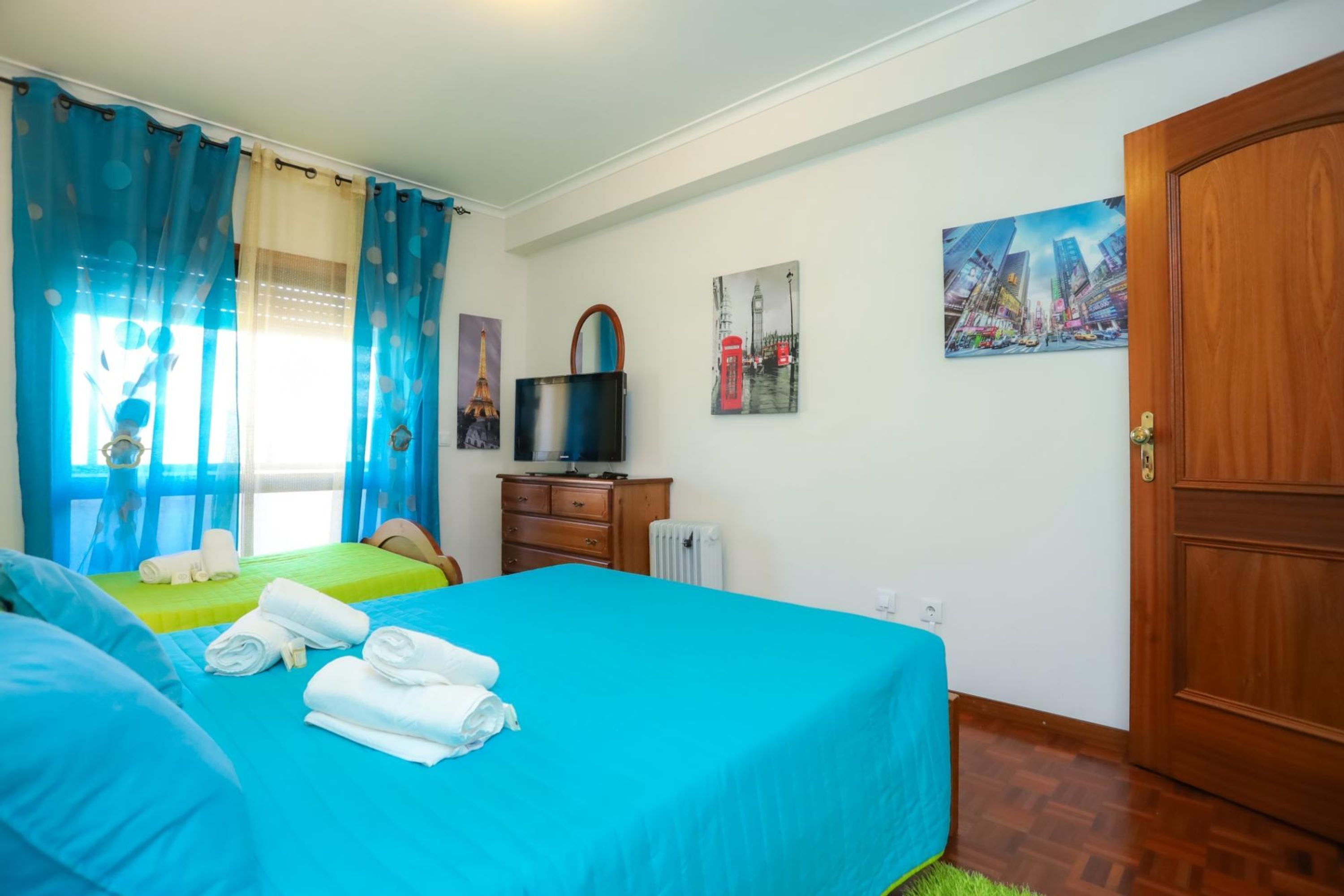 A hotel room with two beds, a television, and artwork on the walls.