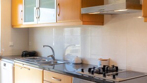 Una cocina moderna con estufa a gas, pileta de acero inoxidable y alacenas de madera.