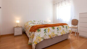 Un dormitorio con cama, mesitas de noche, una silla y cómoda.