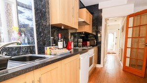 Une cuisine avec des armoires en bois, un plan de travail noir et un plancher en bois.