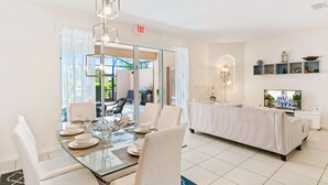 A modern dining area with a glass table, white chairs, and a sofa. - 4722 Terrasonesta Drive (Davenport)